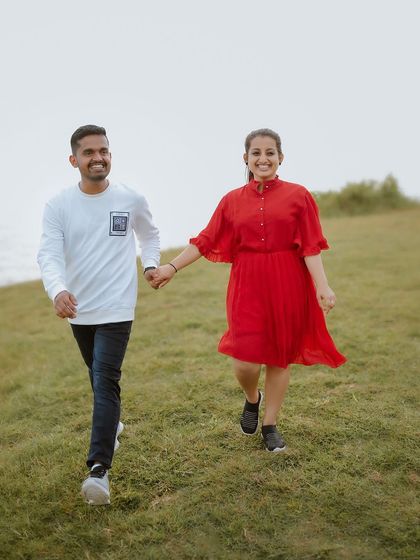 A happy, carefree walk on a grassy hill overlooking the water. The vibrant red dress adds a beautiful pop of color.
