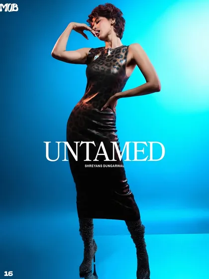 For this "Untamed" series, we used a strong rim light to separate the model from the vibrant blue background. The light traces her silhouette, emphasizing the power in her pose and the texture of the animal-print dress.