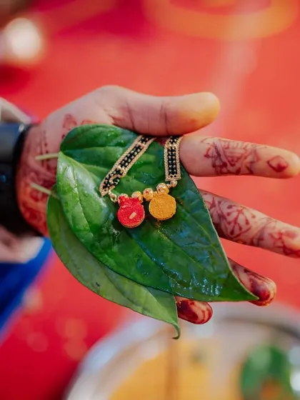 A detail shot of the Mangalsutra resting on a betel leaf in the groom's hand, just before being tied.