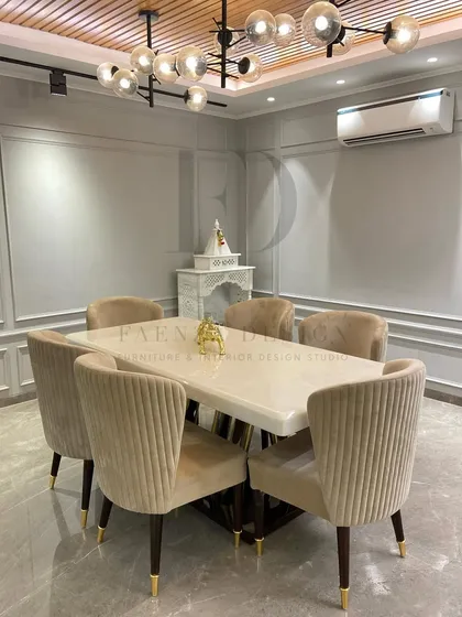 A modern dining set with a white onyx top table and a sculptural gold and dark wood base. The chairs are upholstered in a pleated beige velvet, creating a light and sophisticated dining area.