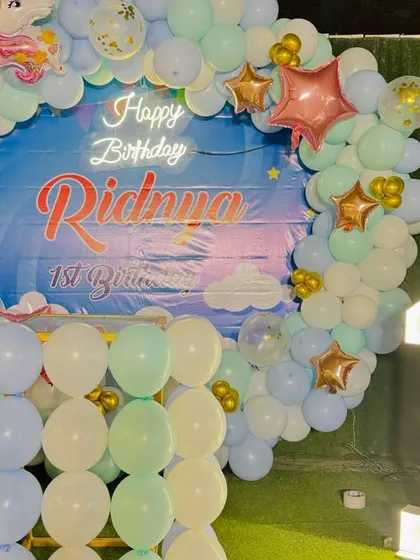 A dreamy unicorn-themed first birthday. This setup features a circular balloon arch in pastel colors, a custom backdrop, and a light-up marquee number '1'.