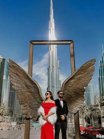 For a touch of modern glamour, we can take our story to international cityscapes. This shot in Dubai, using the iconic Burj Khalifa and the famous angel wings sculpture, creates a powerful and aspirational pre-wedding image.