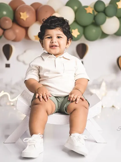 A classic portrait of a one-year-old boy in a hot air balloon themed setup. His sweet smile is just precious.