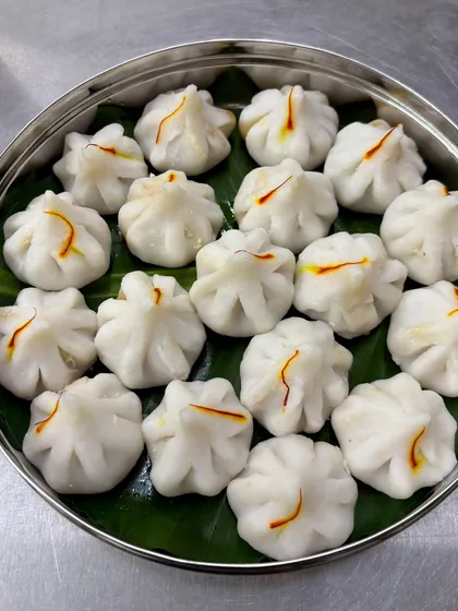 Nothing says celebration like homemade Modak. For Ganesh Chaturthi, we prepare these delicate steamed rice-flour dumplings filled with a sweet mixture of coconut and jaggery. Each one is carefully shaped by hand and topped with a strand of saffron, made just the way my dadi taught me.
