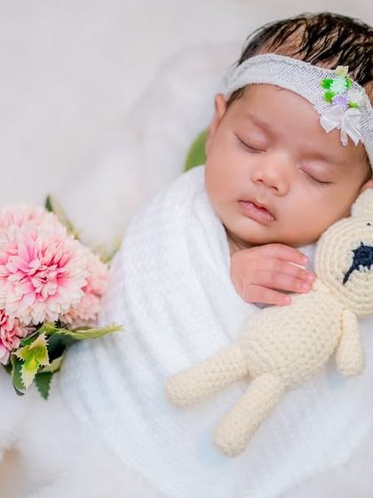 A classic newborn pose, with the baby snuggled up to a soft, knitted teddy bear. This all-white theme with a hint of pink creates a dreamy, cloud-like effect, emphasizing the innocence of this moment.