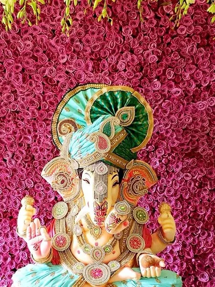 The vibrant colors of the Ganpati idol stand out beautifully against this solid wall of bright pink roses, creating a joyful and striking image.