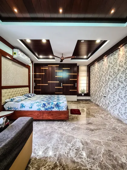 In this luxurious bedroom, I combined rich materials to create a warm and opulent feel. The design features polished Italian marble flooring, a floor-to-ceiling wardrobe with dark wood and custom inlays, and a damask pattern accent wall, all tied together by a layered false ceiling.
