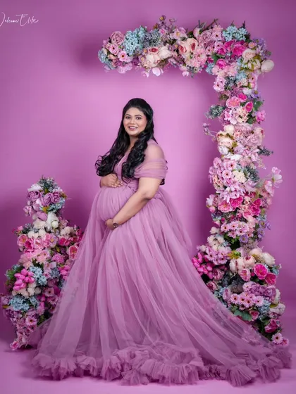 A stunning maternity shoot in a lavender gown. The soft, ethereal makeup complements the floral theme perfectly.