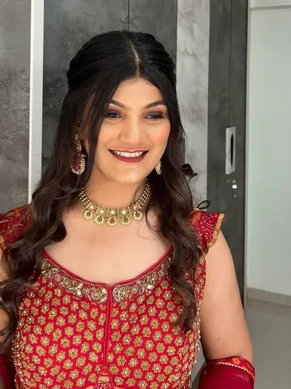 This client is ready for a sangeet or reception in her beautiful red and gold lehenga. The makeup is glamorous but still soft, with a focus on her eyes and a radiant smile.