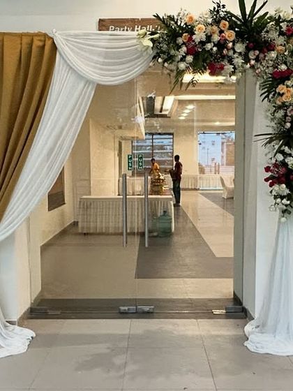 The entrance for the 75th birthday party, with drapes and a floral arch that match the golden theme of the main stage.