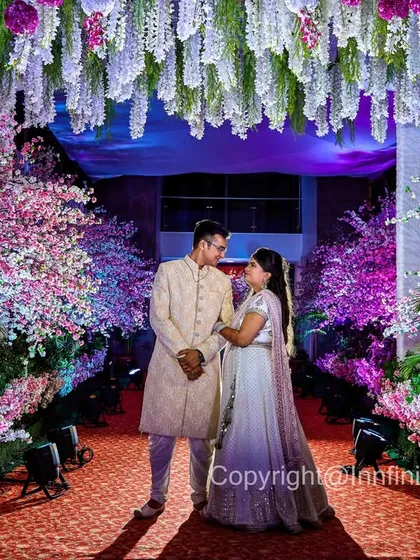A wide shot of the couple framed by a stunning floral archway at their engagement venue. This type of photo showcases the scale and beauty of your event decor while keeping the focus on your story.
