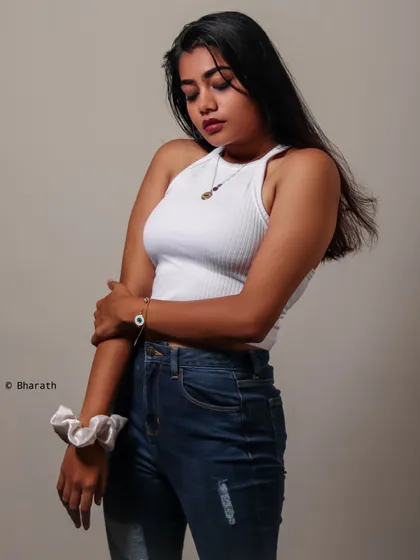 A pensive, looking-down pose that adds a touch of moodiness to the simple, casual outfit.