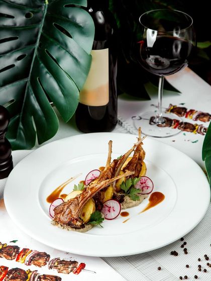 A perfect pairing of food and wine. These tender lamb ribs are served with sliced radishes and a rich sauce, showcasing a classic dish executed with fine dining precision.