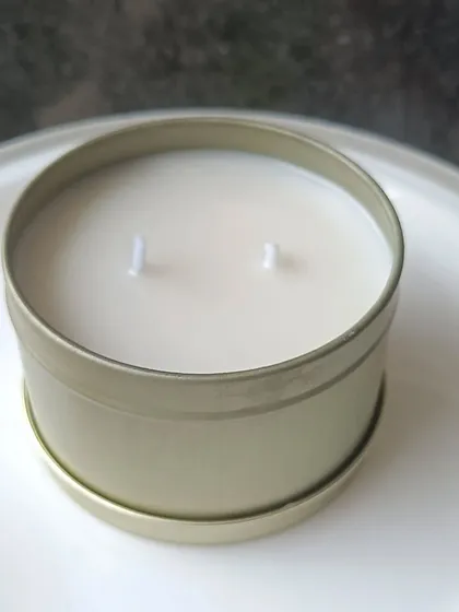 A view of the two-wick soy candle inside the golden tin jar.