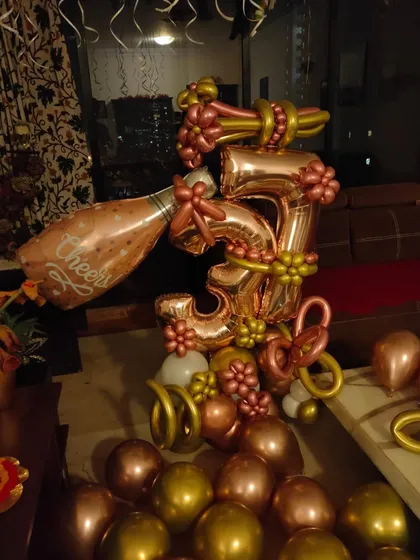 A custom balloon bouquet for a 35th birthday, featuring a champagne bottle balloon and numbers made from rose gold balloons.