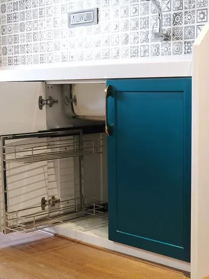 A look inside the cabinetry reveals a smart under-sink pull-out basket system. This solution utilizes an often-wasted space, keeping cleaning supplies organized and within easy reach.