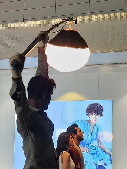 The classic tungsten gemball, or lantern light, is still a valuable tool for creating soft, omnidirectional light. Here, a crew member positions one for a TVC shoot, demonstrating that we use both new and conventional tools to get the job done.