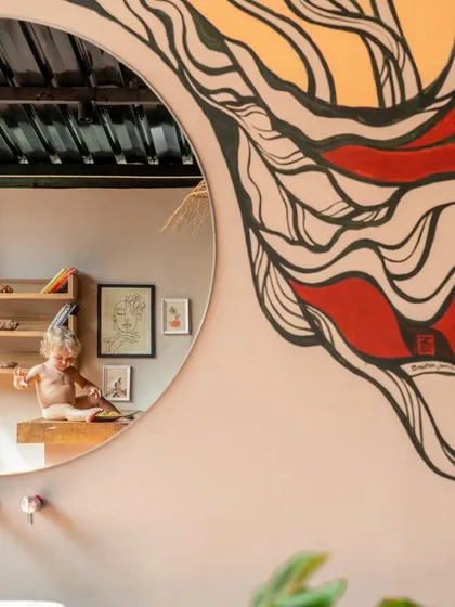 Art and reflection are woven into the design of Unallome. A large, circular mirror reflects a custom mural, adding a layer of creative expression to the bathroom space while maintaining a connection to the earthy, organic aesthetic.