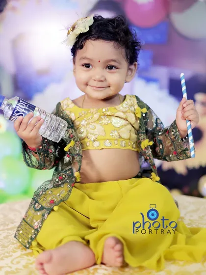 A charming portrait of the little girl sitting and posing with a water bottle and straw, looking like a tiny model.