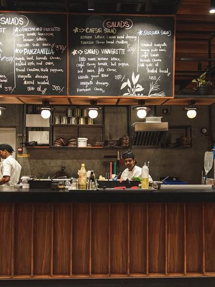 The heart of our Palace Road outlet: the open kitchen counter with the brick oven in the background and our menu displayed on chalkboards above.