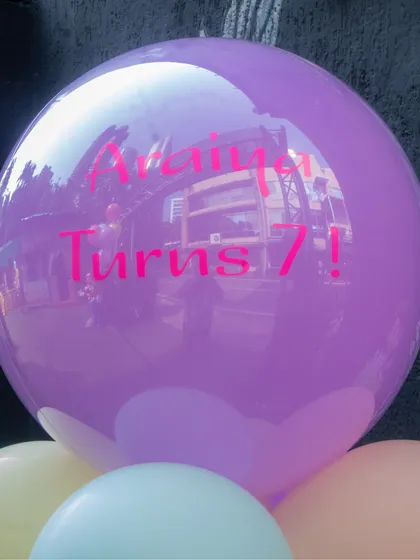 A close up of a personalized balloon for a 7th birthday. The large purple balloon features the message "Avaiya Turns 7!" in bright pink, showing how we can customize details to match your party's theme.