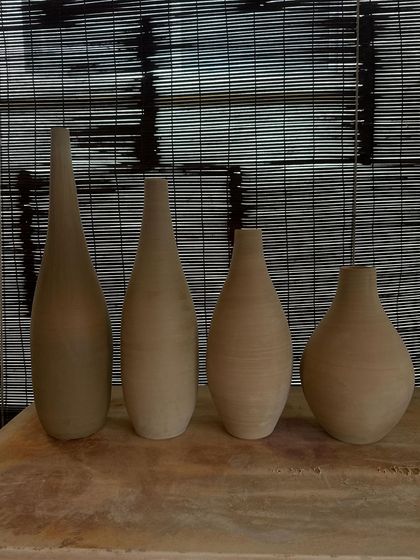 A collection of large, unglazed vases in various shapes and sizes. Each one is thrown on the wheel and showcases a different form, from classic curves to textured surfaces.