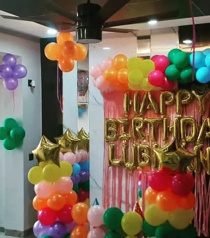 This view shows how the classic balloon decorations can transform a room corner. I use balloon clusters on the walls and ceiling to complement the main backdrop, creating a full party atmosphere.