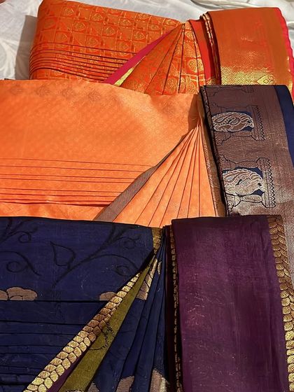 A set of sarees in orange and blue tones, ready to be folded and organized.