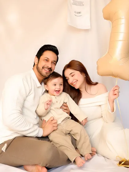 A happy family of three poses with a "1" balloon to celebrate their son's first birthday. Their coordinated outfits and joyful interactions create a perfect family portrait.