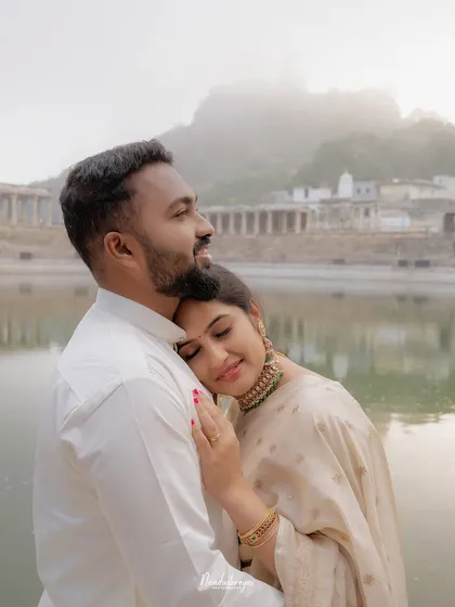 A quiet, heartfelt embrace between a couple by the serene temple pond at Melukote, with misty hills in the background. This image captures the pure, unscripted emotion and natural chemistry that I focus on in every shoot.