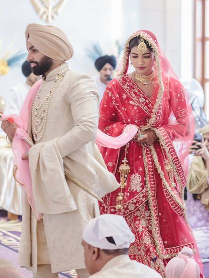 A side view of the Laavan Pheras, showing the bride and groom walking together. This angle highlights the bride's beautiful lehenga and the solemnity of the ritual.