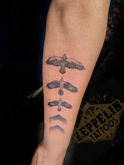 A conceptual tattoo showing the evolution of a bird in flight, transforming into arrows pointing forward. It symbolizes growth, progress, and always moving ahead.