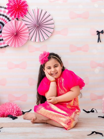 Once upon a shimmer. This little princess is all smiles in her sparkly pink dress, sitting in a fun, graphic-patterned set.