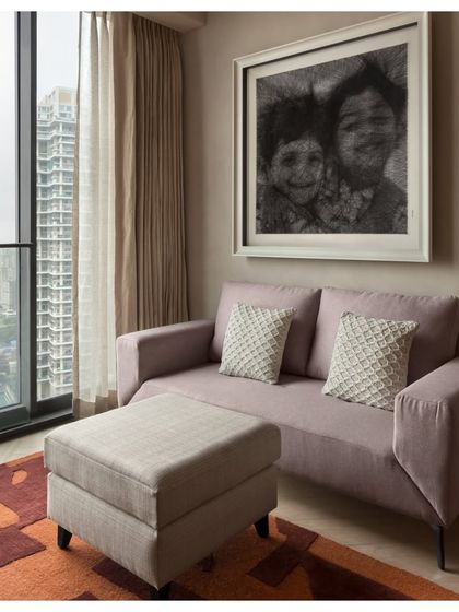 A cozy seating nook in the East Coast Residence, featuring a small sofa and ottoman. A personalized, pixelated artwork hangs above, adding a deeply personal touch to the room.