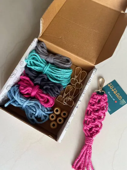 Here is a peek inside the box! You get five bundles of soft 3mm cotton cord, five golden hooks, and wooden beads, plus a finished pink keychain to show you what is possible. It is a perfect sustainable DIY gift idea.