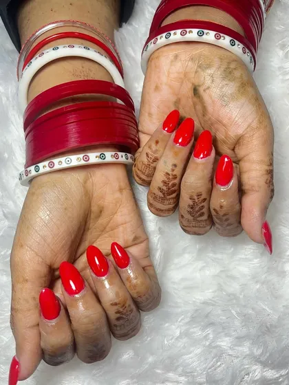 This photo shows how beautifully a simple, bold red nail can complement traditional wedding bangles. The acrylic extensions provide a perfect canvas for this striking and classic look.