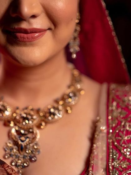 A close-up shot focusing on the bride's serene smile and the intricate details of her wedding necklace.