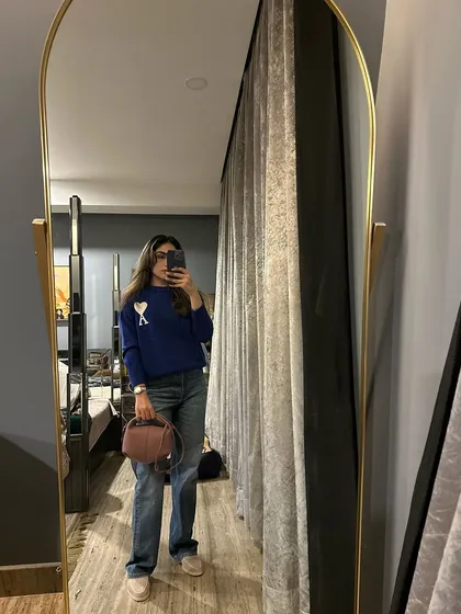 A casual winter outfit featuring a blue sweater and baggy jeans. This is a comfortable and easy look for a relaxed day.