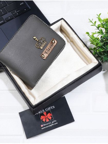 A sophisticated grey leather wallet personalized with a crown charm, shown in its gift box.