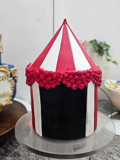 The top tier of the circus cake during its creation, showing the fondant tent structure.