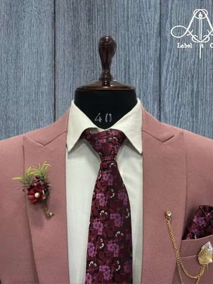 A close-up of the dusty pink suit, showing the beautiful floral tie and lapel pin that complete this stylish and contemporary look.