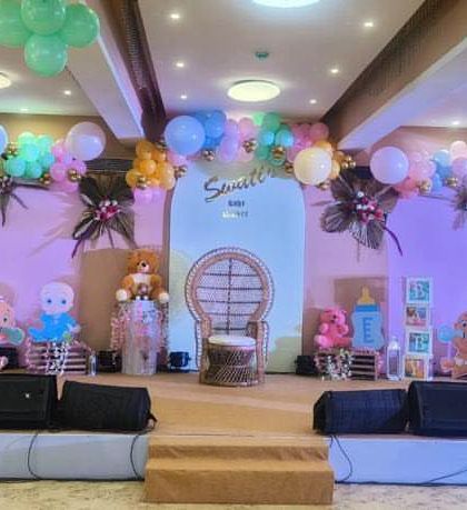 An alternate view of our large-scale baby shower stage decoration. This angle shows the depth of the balloon arrangements and the placement of various props like baby blocks and bottles across the stage.