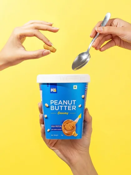 This conceptual hand model shot for a peanut butter brand is playful and creative. The composition suggests the ingredients are being magically added, turning a simple product into something more exciting.