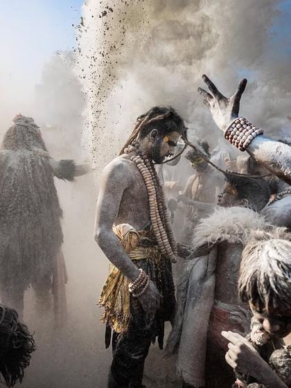 A wider view of the Masan Holi celebration, showing the chaotic dance amidst clouds of ash from the cremation grounds. The scene is painterly and full of movement.