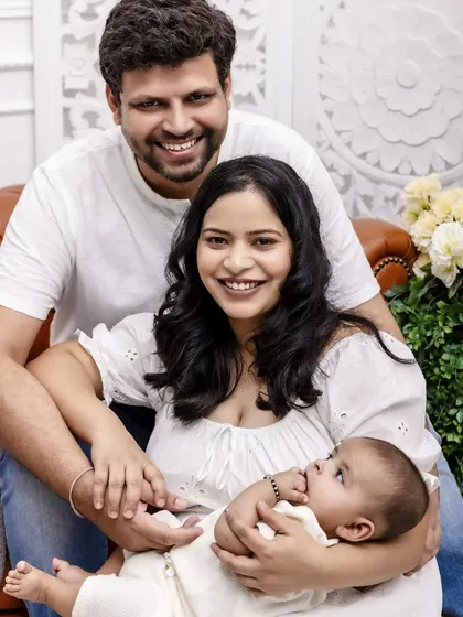 A happy family of three smiling for the camera. This bright and joyful portrait captures the love and excitement of new parenthood.