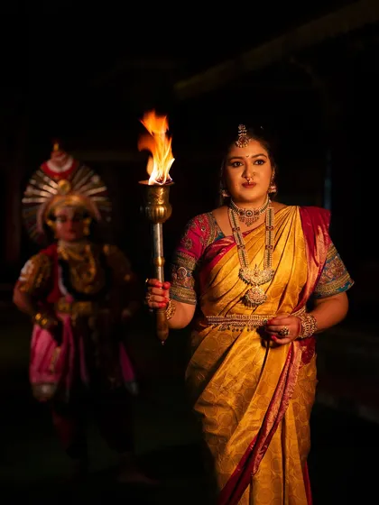 A full-frame shot of the "Belaku" concept, capturing the traditional attire and the symbolic torch in a powerful composition.