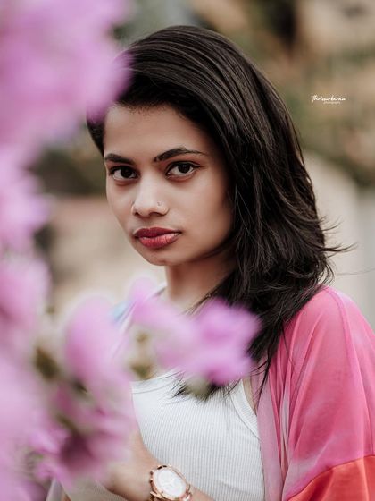 A creative portrait using flowers in the foreground to frame the model's face. This technique adds depth and a touch of artistry.