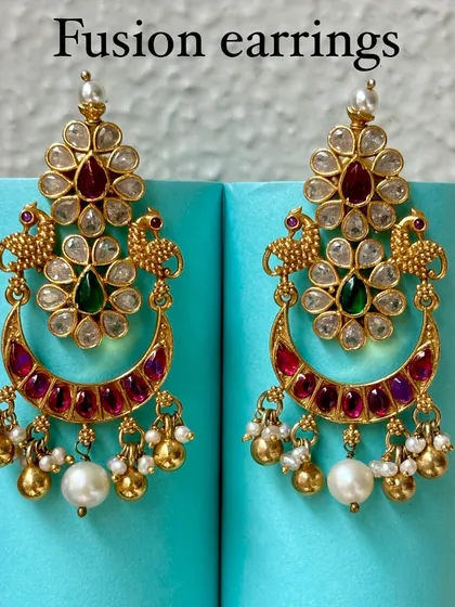 Premium silver gold-plated fusion earrings. This pair features a classic chaandbali design with Kundan work, peacock motifs, and pearl drops, perfect for weddings and festive occasions.