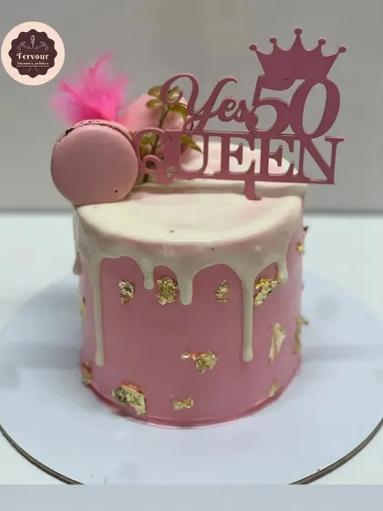 A "Yes 50 Queen" cake for a fabulous 50th birthday. This pink drip cake is decorated with gold leaf, macarons, and a feather for a touch of glam.