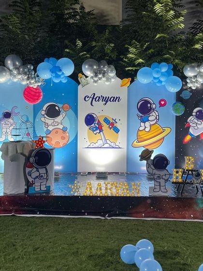 An out of this world space and astronaut theme for an outdoor party, with custom backdrops, planet props, and a starry floor mat.